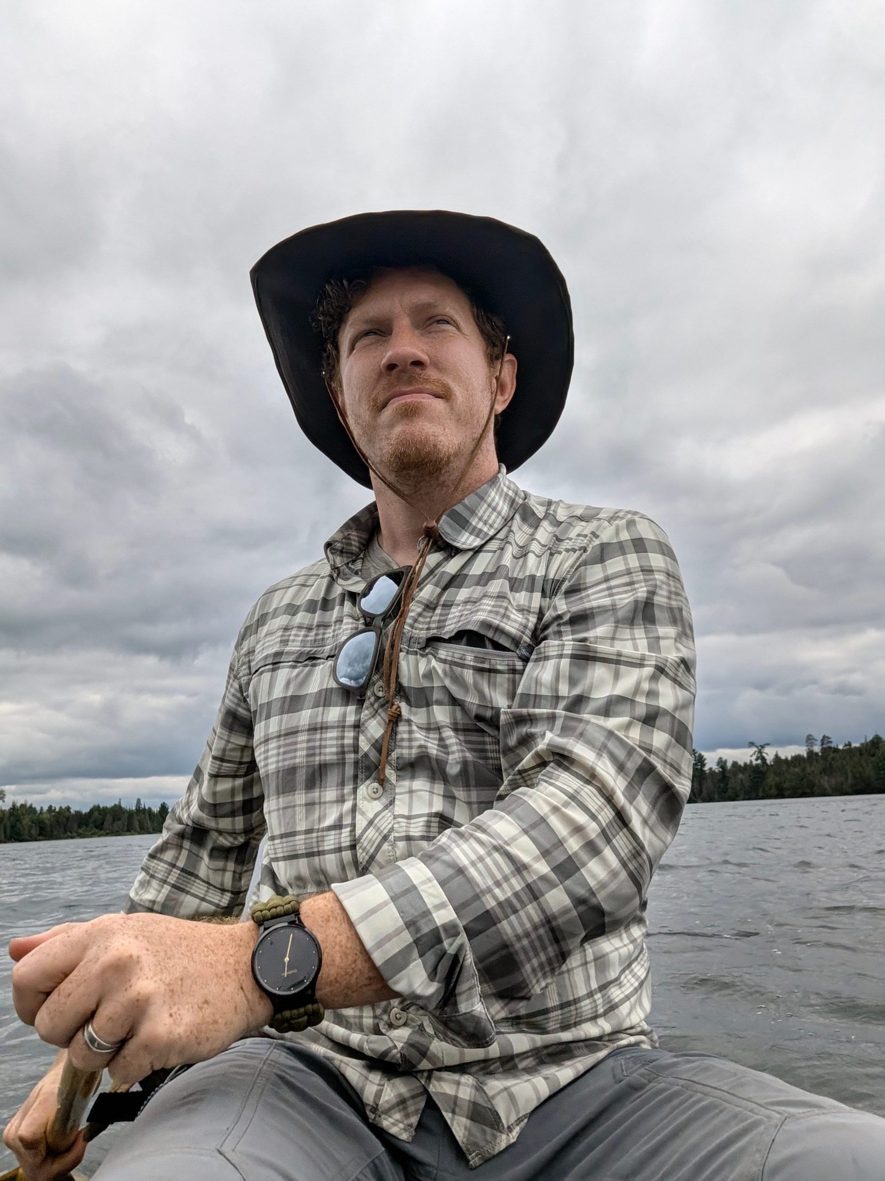 John in a wide-brim hat paddling a canoe