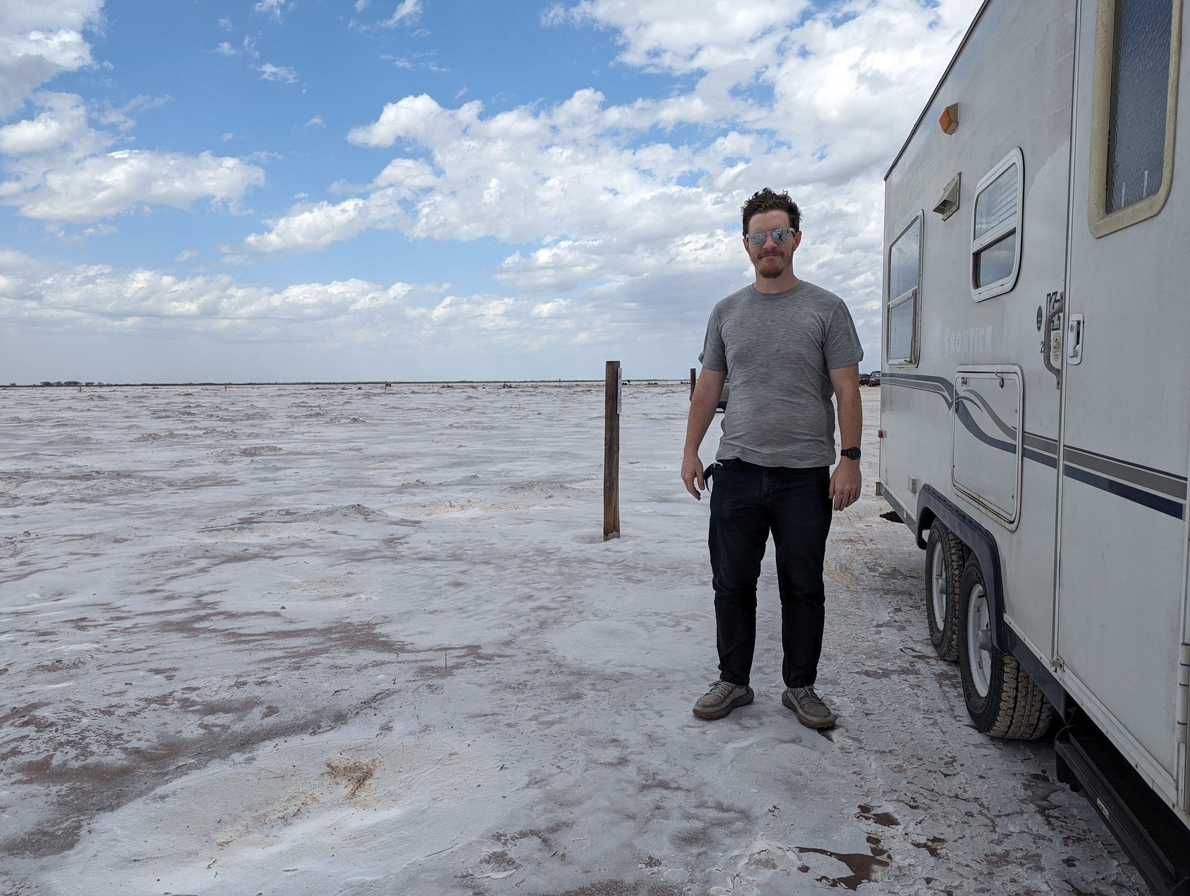 John standing next to the camper on a salt flat