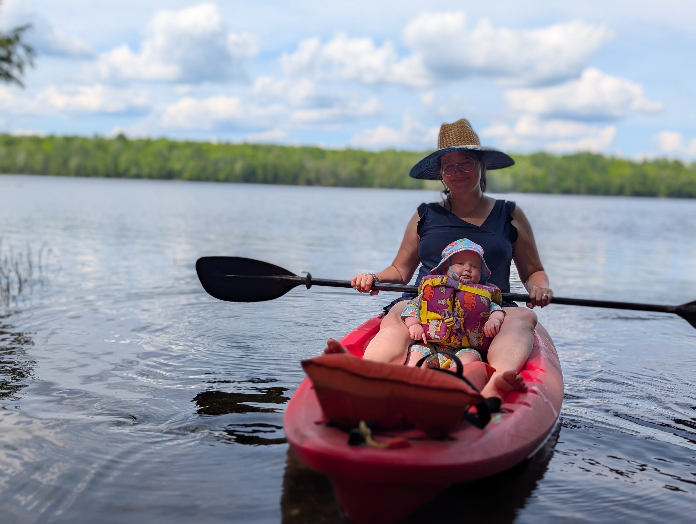 Woman and child paddling a red kayak on a lake