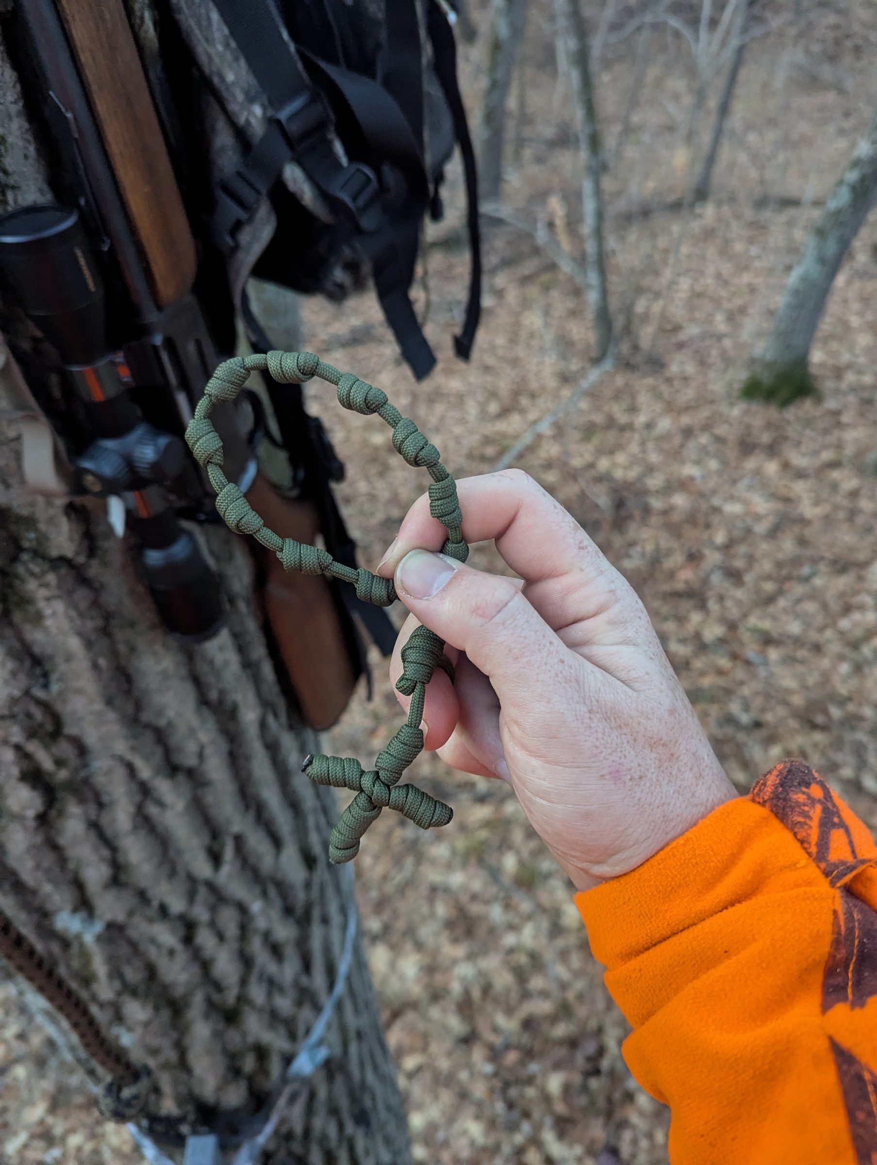 Hand holding a paracord rosary in a deer stand